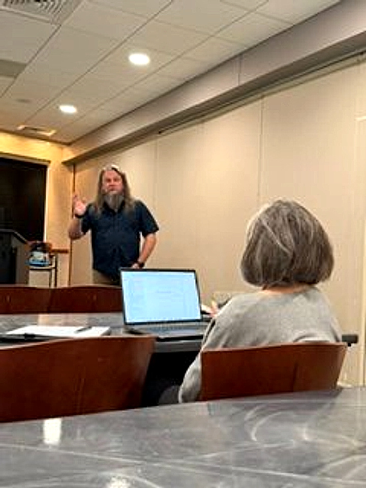 Christopher Gulledge speaking with his hand raised while a participant follows along on her laptop in the foreground